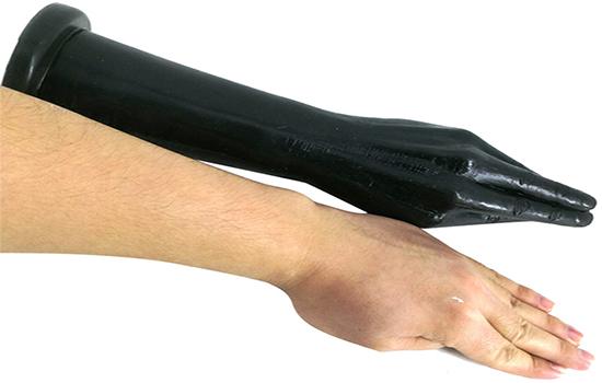 A realistic black fisting dildo next to an arm